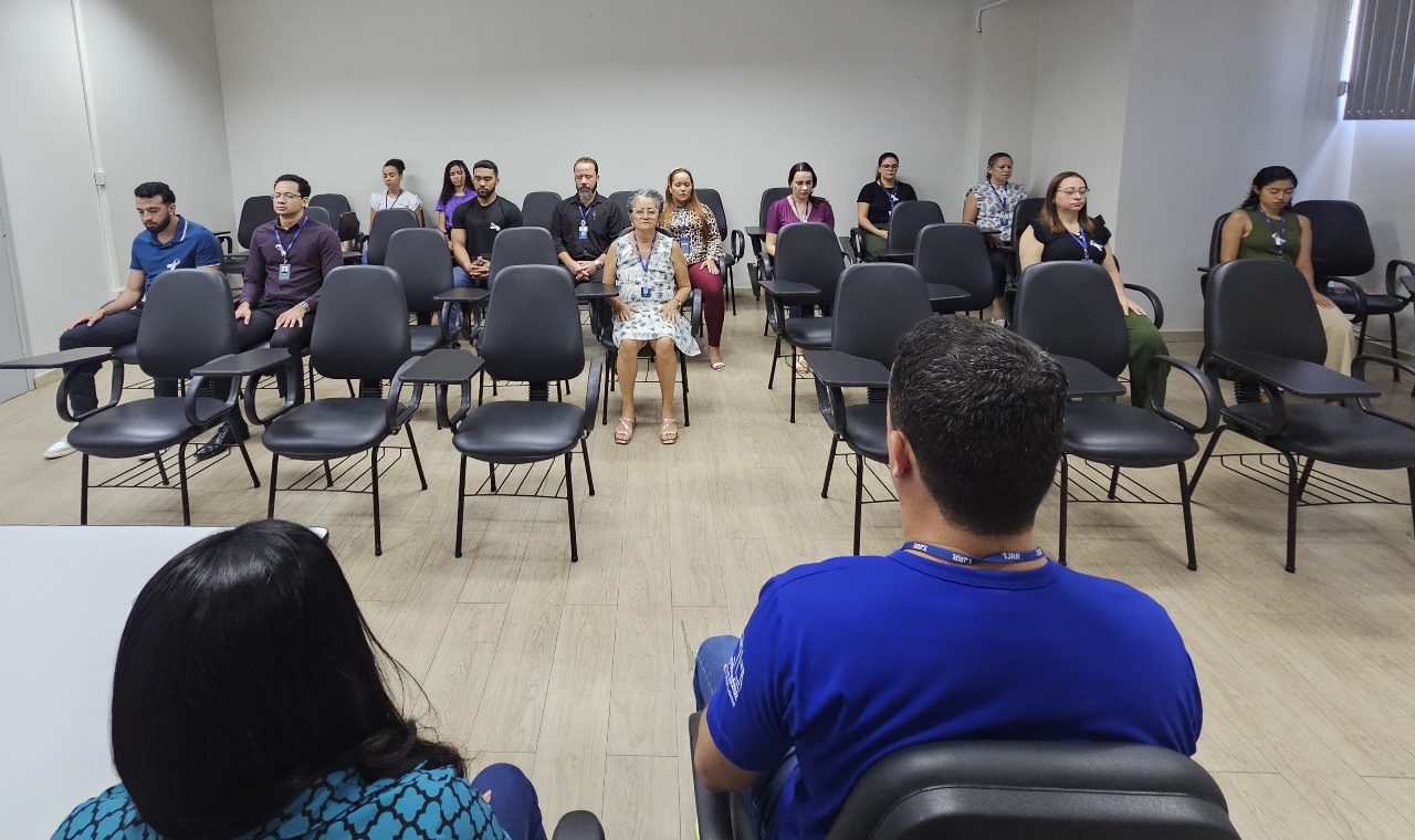 imagem colorida mostra integrantes do TJRR sentados em diferentes fileiras de cadeiras de olhos fechados enquanto fazem a prática de meditação. imagem colorida mostra integrantes do TJRR sentados em diferentes fileiras de cadeiras de olhos fechados enquanto fazem a prática de meditação.