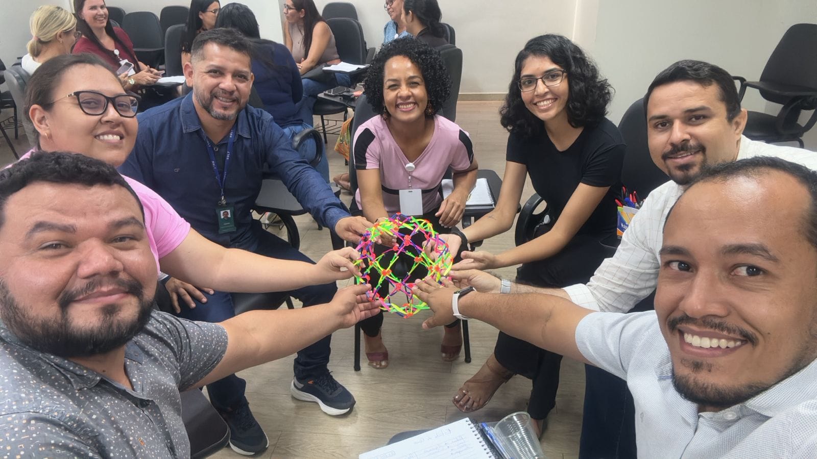 foto colorida de 7 pessoas segurando um objeto colorido feito de elástico