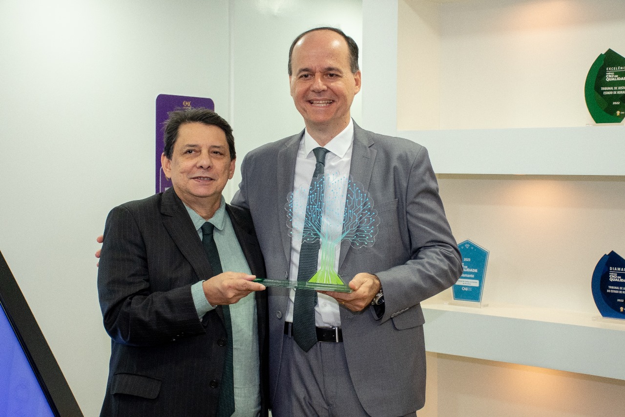 foto colorida do Presidente do TJRR, Jésus Nascimento, ao lado do Desembargador Cristovão Suter pousando para a fotografia segurando o prêmio CNJ de qualidade. 
