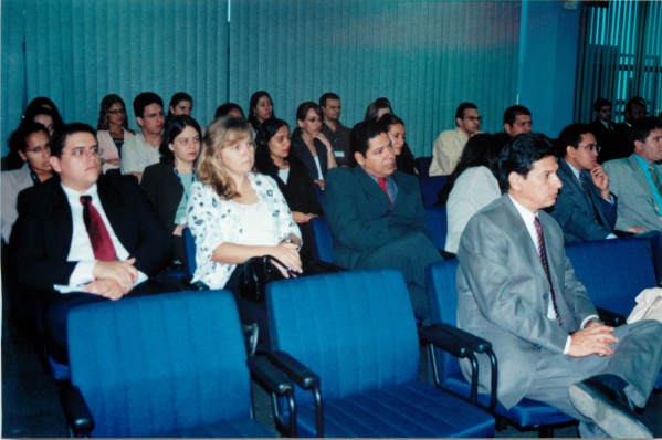 Foto antiga de pessoas sentadas, assistindo sessão no tribunal. 