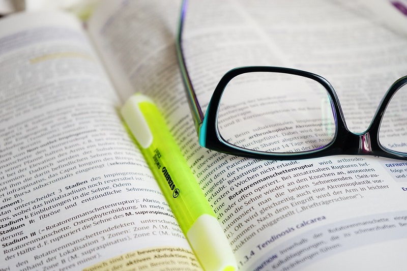 Um livro, um marca pagina e um oculos na foto