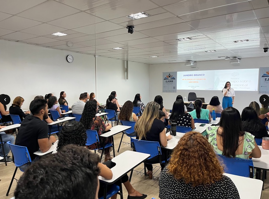 foto colorida de uma sala com pessoas sentadas em cadeiras escolar em direção a um quadro