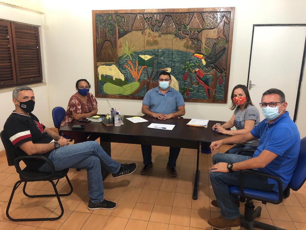 Servidores do tribunal de Justiça e representantes da Univirr sentados ao redor de mesa, em uma sala, com quadro grande atrás.