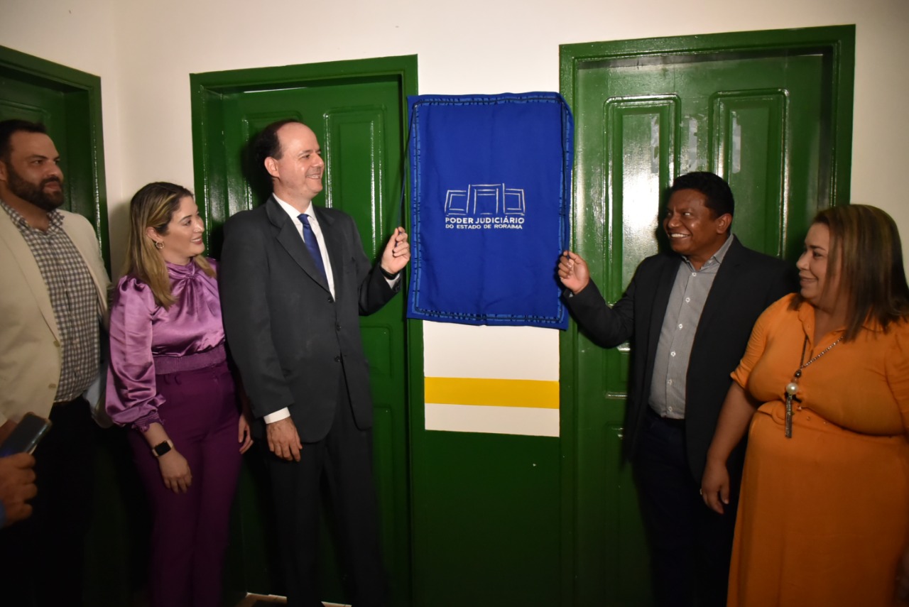 Foto colorida mostra à esquerda o presidente, desembargador Cristóvão Súter, puxando a fita de inauguração da unidade de Caroebe, ao lado da dra. e juíza titular da comarca de São Luiz do Anauá, Rafaella Holanda e do dr. e juiz auxiliar do CNJ, Dorotheo Neto. À direita da imagem, está o prefeito de Caroebe, Osmar Filho, segurando a outra corda da faixa de inauguração, ao lado da primeira-dama, Márcia Marques. 