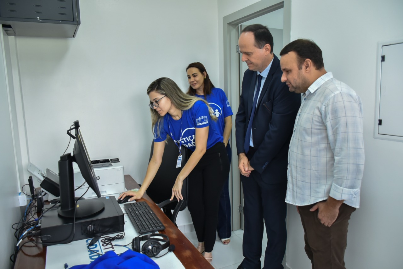 imagem colorida e quadrada contém o presidente do Tribunal de Justiça de Roraima, desembargador Cristóvão Suter, ao lado do prefeito do município de Cantá, André Castro,  e mais duas servidoras do TJRR usando a camisa azul com a logo do Justiça Cidadã, analisando computador durante inauguração do Posto de atendimento do município. 