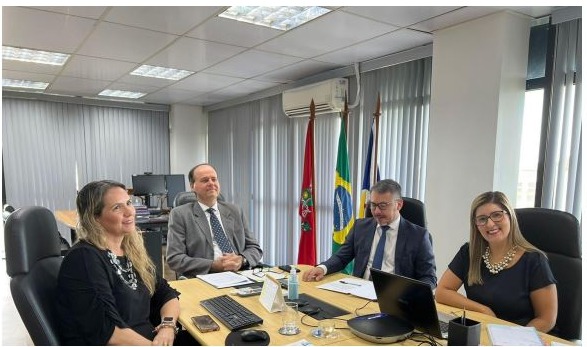 Imagem colorida em formato retangular mostra  o desembargador Cristóvão Suter em uma sala de reuniões com um servidor e duas servidoras do TJRR. 