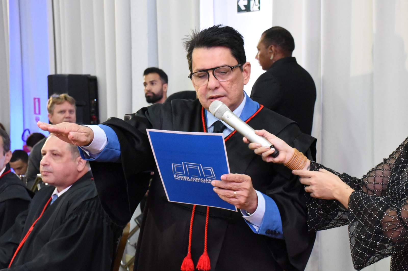 Imagem colorida mostra o presidente do Tribunal de Justiça de Roraima, Jésus Nascimento, com a mão direita erguida durante a leitura do Juramento.