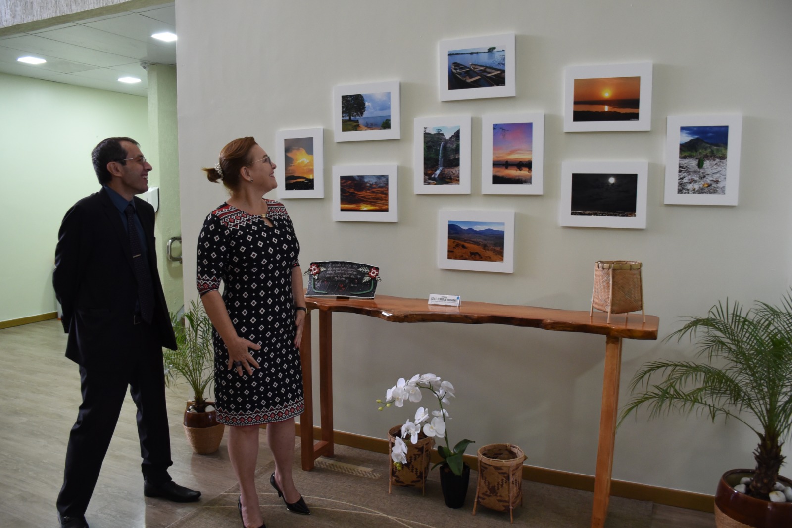 Desembargador Erick Linhares e a desembargadora Elaine Bianchi, em frente à exposição de fotos, olhando para os quadros. 