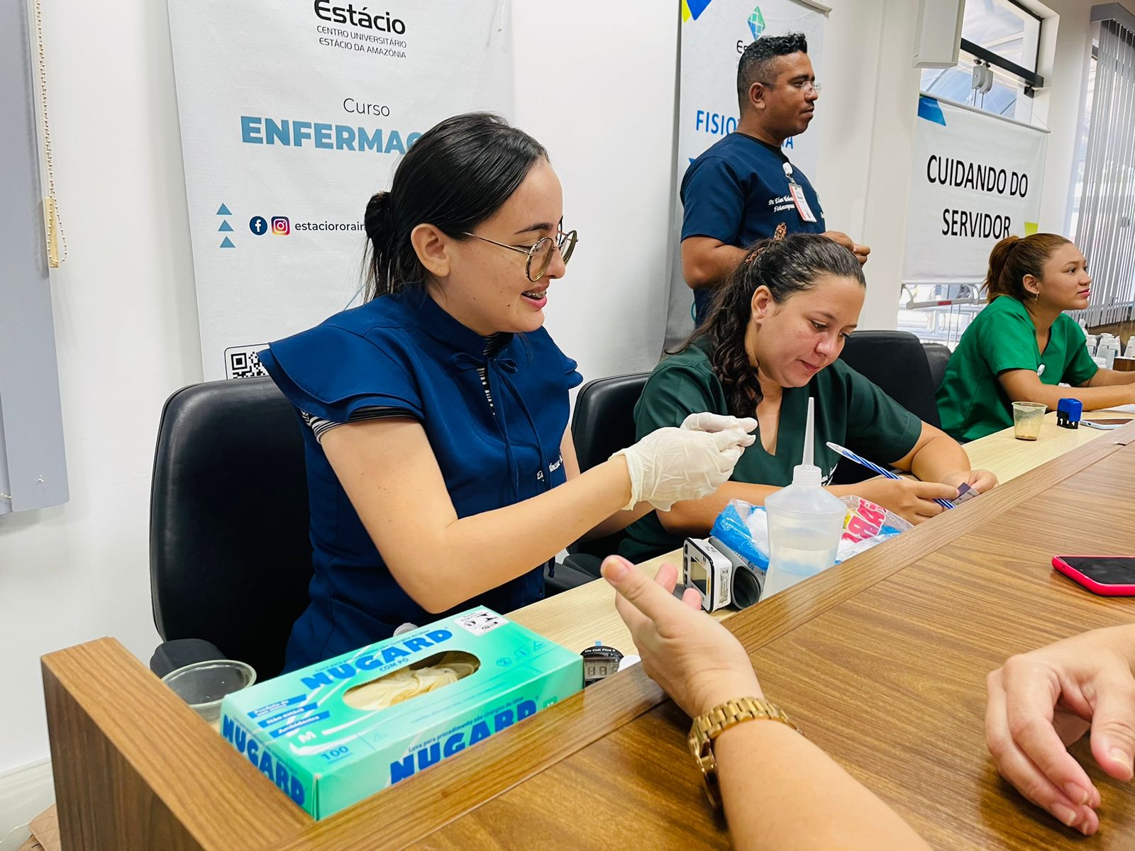 Imagem colorida,mostra mulheres fazendo atendimento aos servidores do TJRR durante a semana de atividades.