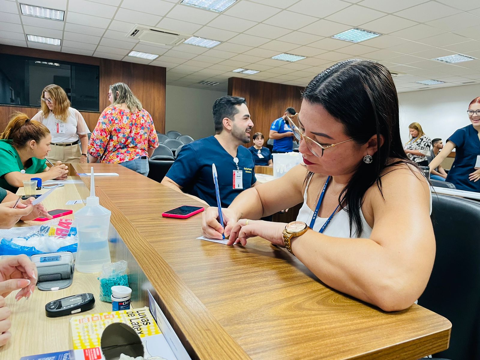 Foto colorida de servidora escrevendo em um balcão durante atendimentos da semana do servidor no TJRR. 