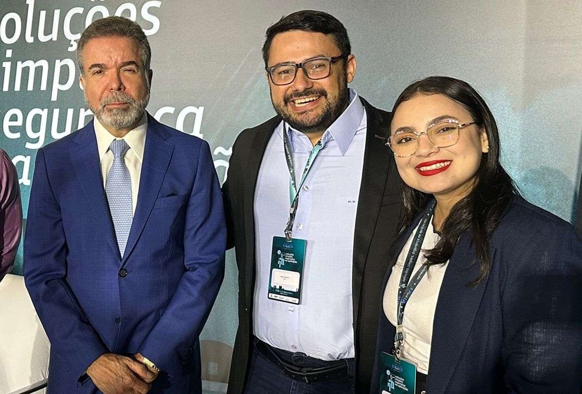 foto colorida mostra três pessoas posando para a foto durante o Congresso