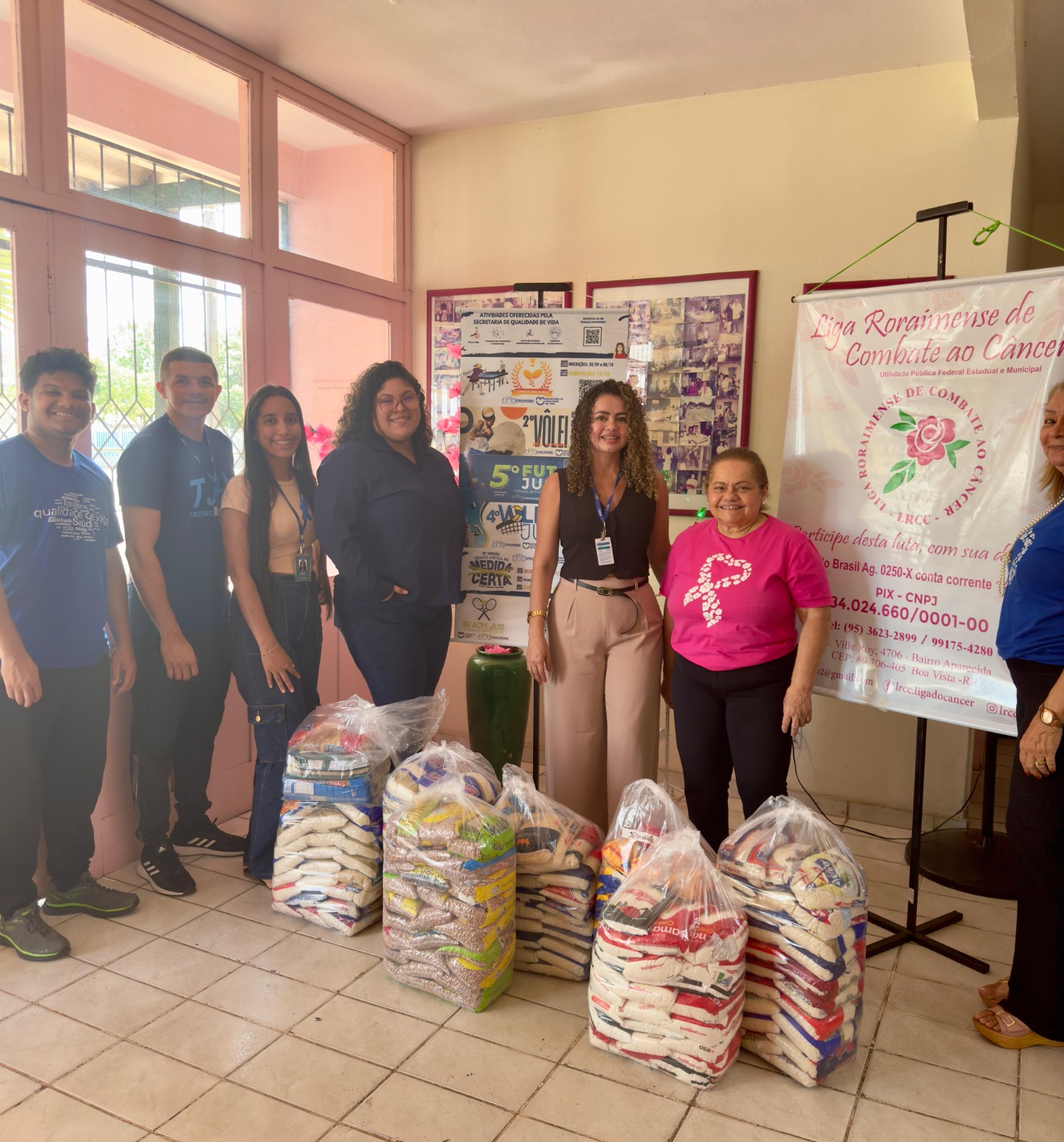 foto colorida mostra sete pessoas em pé posando para a foto com a doação de alimentos