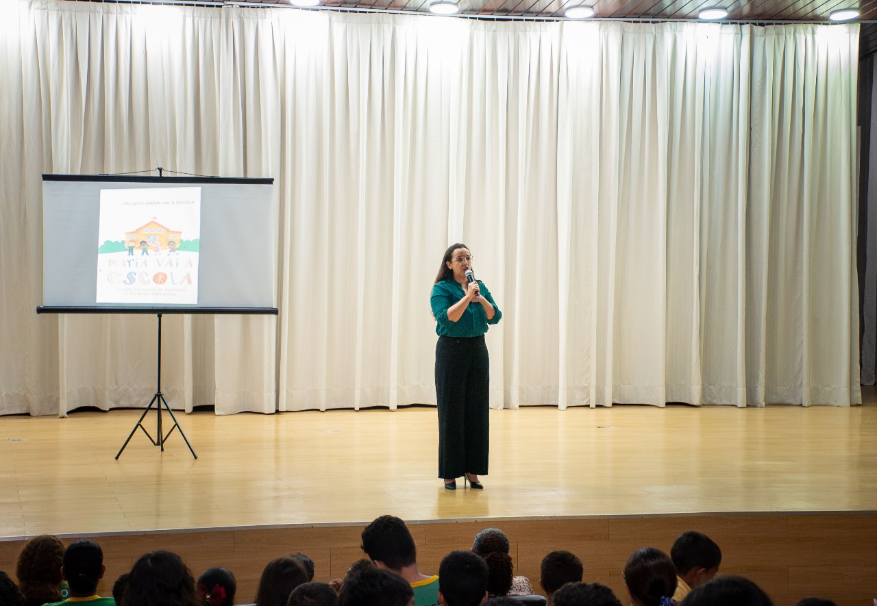 Foto colorida mostra a juiza Suelen Alves discursando em cima do palco do auditorio do Fórum Cível Advogado Sobral Pinto