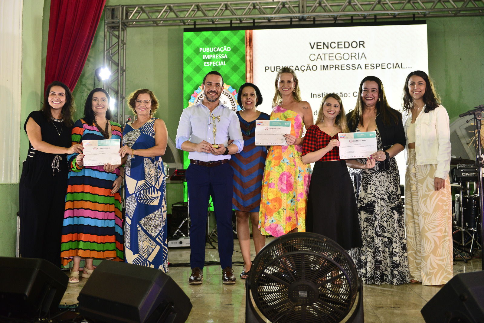 Foto colorida mostrando pessoas posando para foto durante entrega de premiação do Conbrascom 