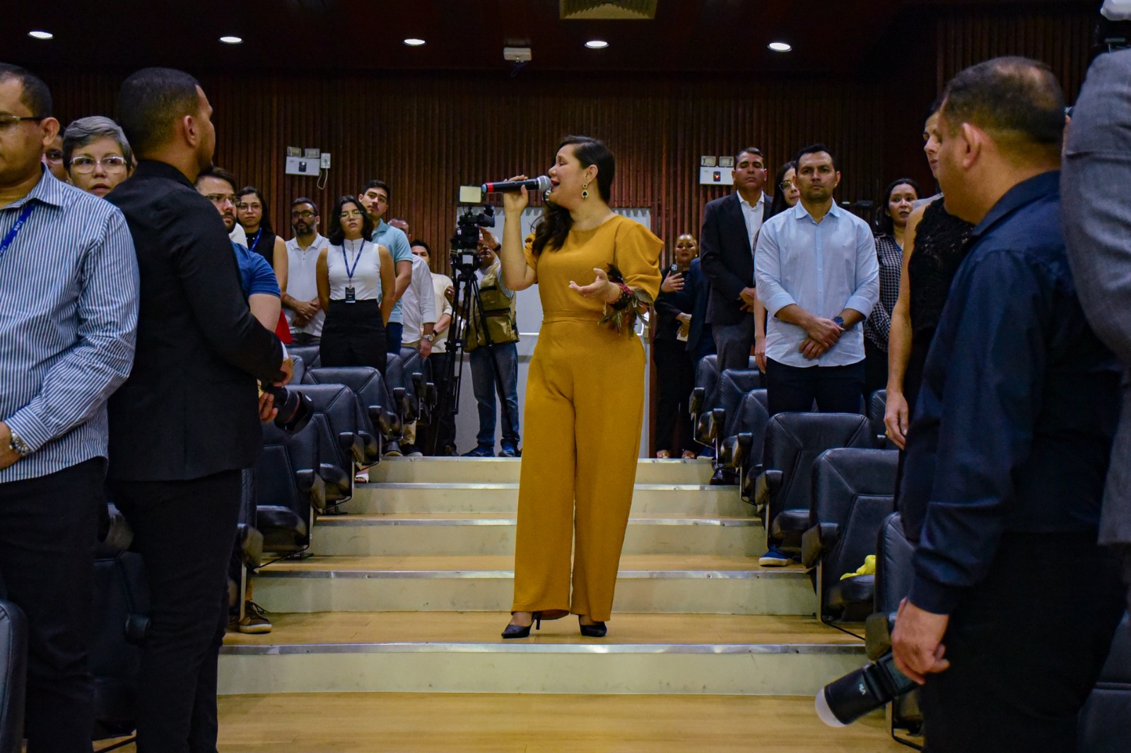 foto colorida de uma mulher vestida de amarelo cantando 