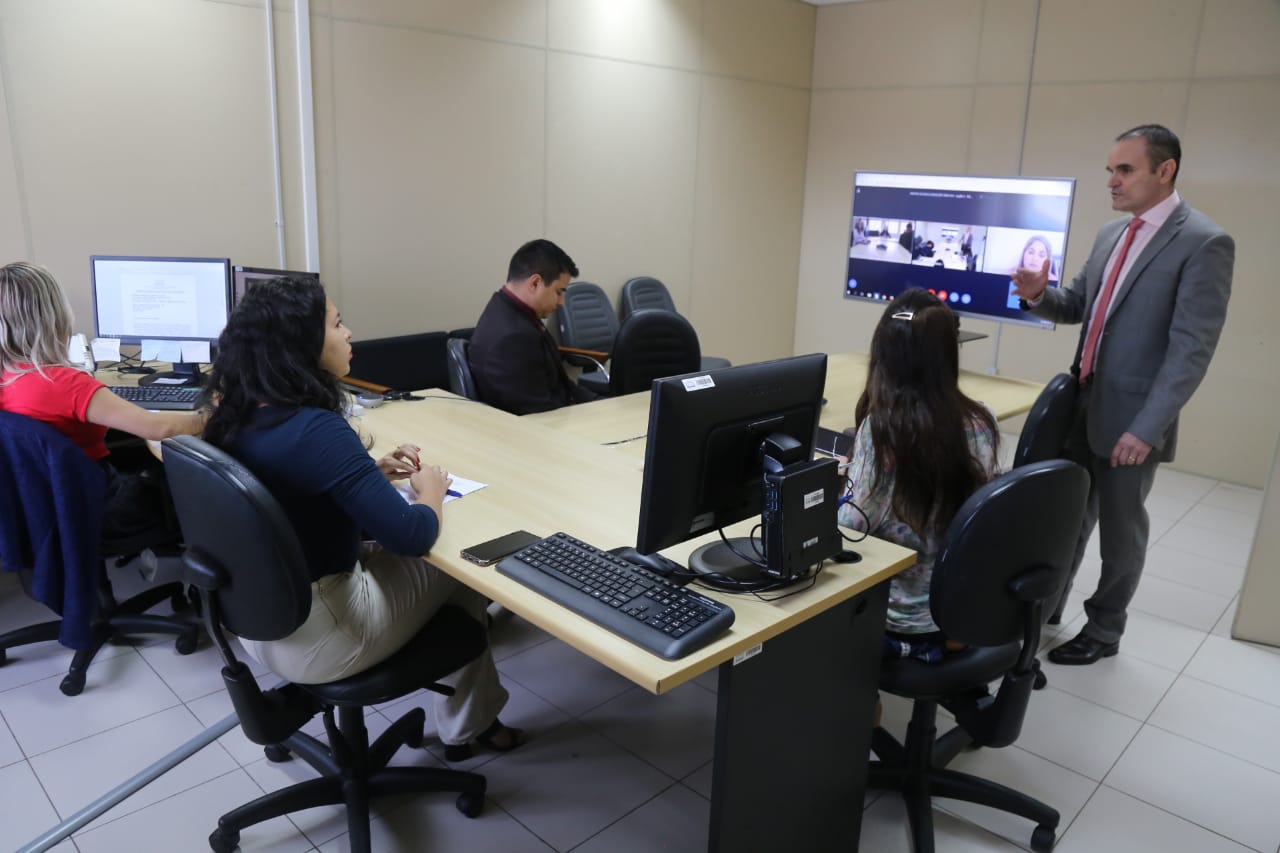 Equipe do 2o Juizado Especial e as partes do processo reunidos em uma sala durante a videoconferência entre o Brasil e Portugal