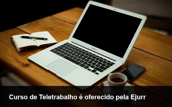 Na imagem aparece um notbook, um bloco de anotações, uma xícara e um telefone celular. 