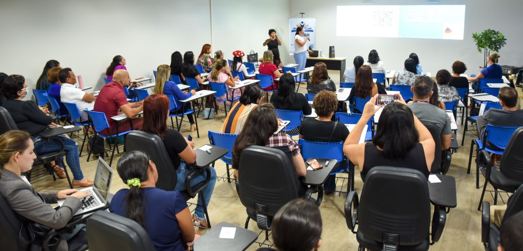 foto colorida de uma turma de servidores sentados em cadeiras de escolares 