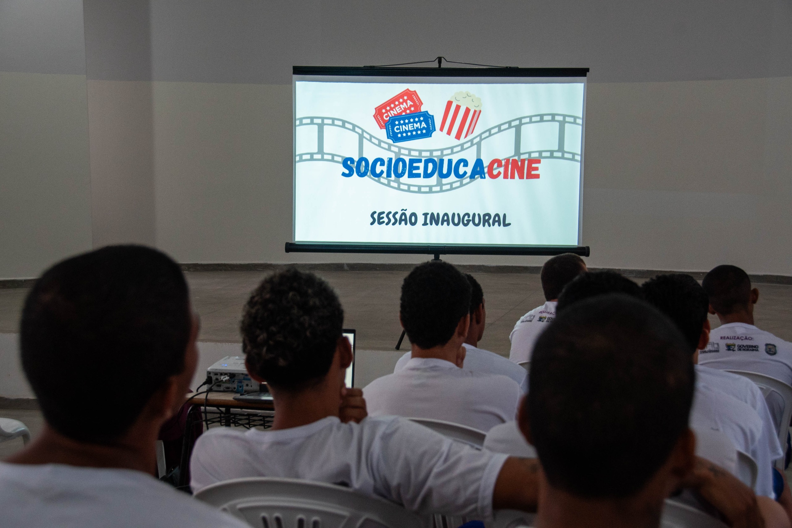 foto colorida tirada por traz mostrando jovens do CSE direcionados ao slide que está escrito "socioeducacine"