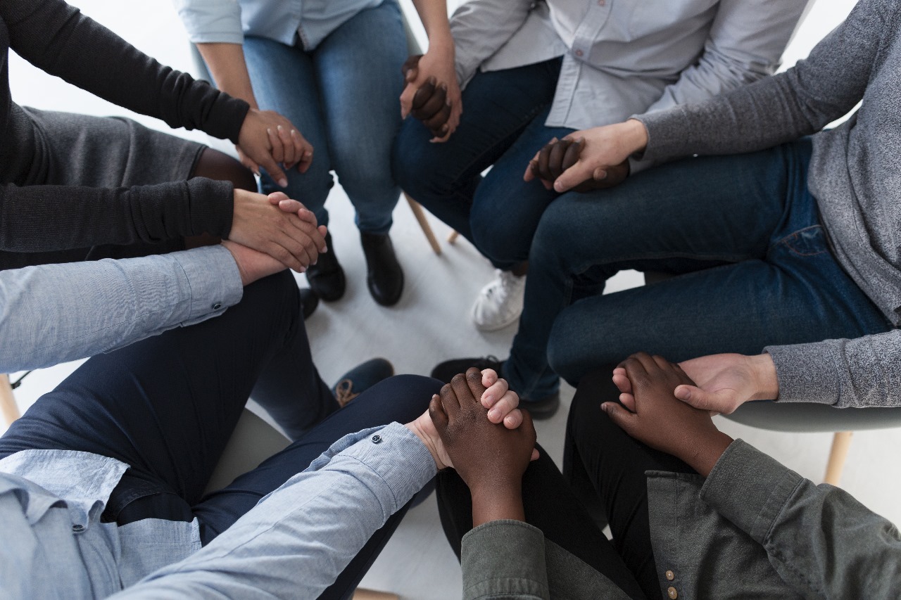 Imagem mostra pessoas em uma roda dando as mãos uns para os outros Imagem mostra pessoas em uma roda dando as mãos uns para os outros